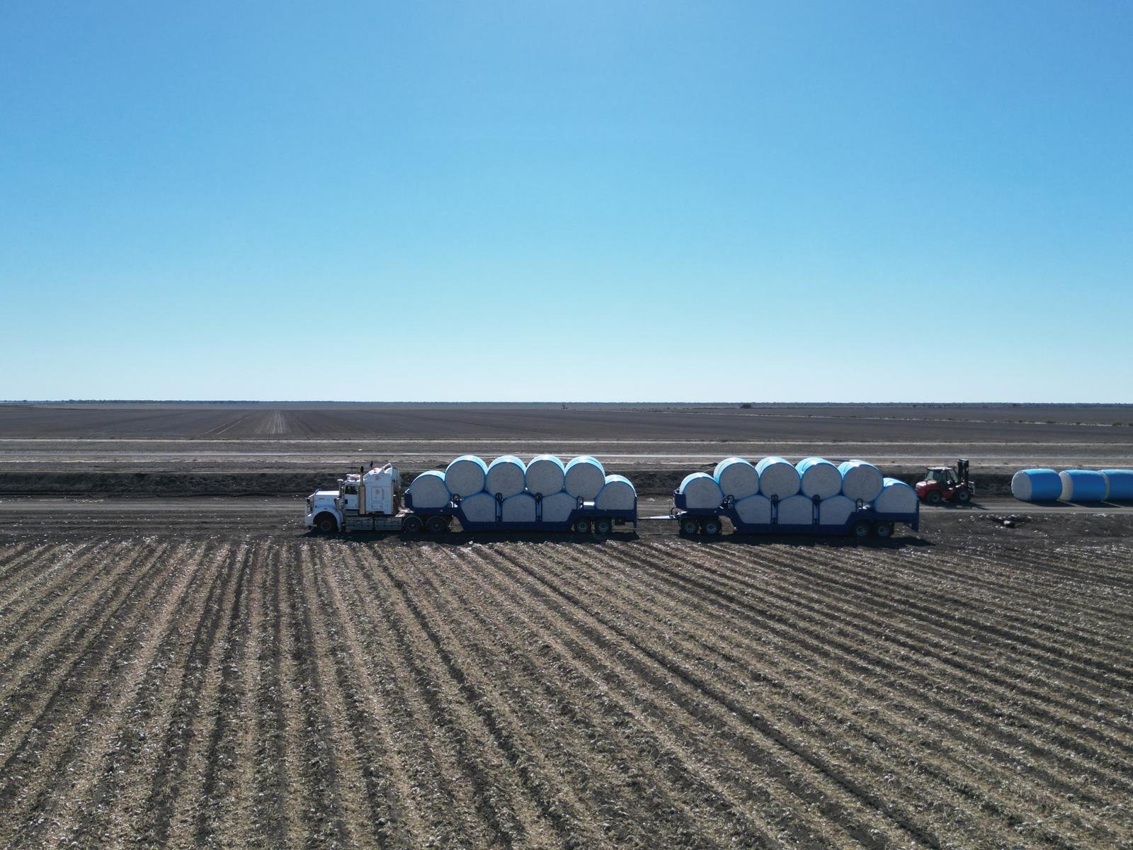 Truck loaded with round cotton bales on the field edge