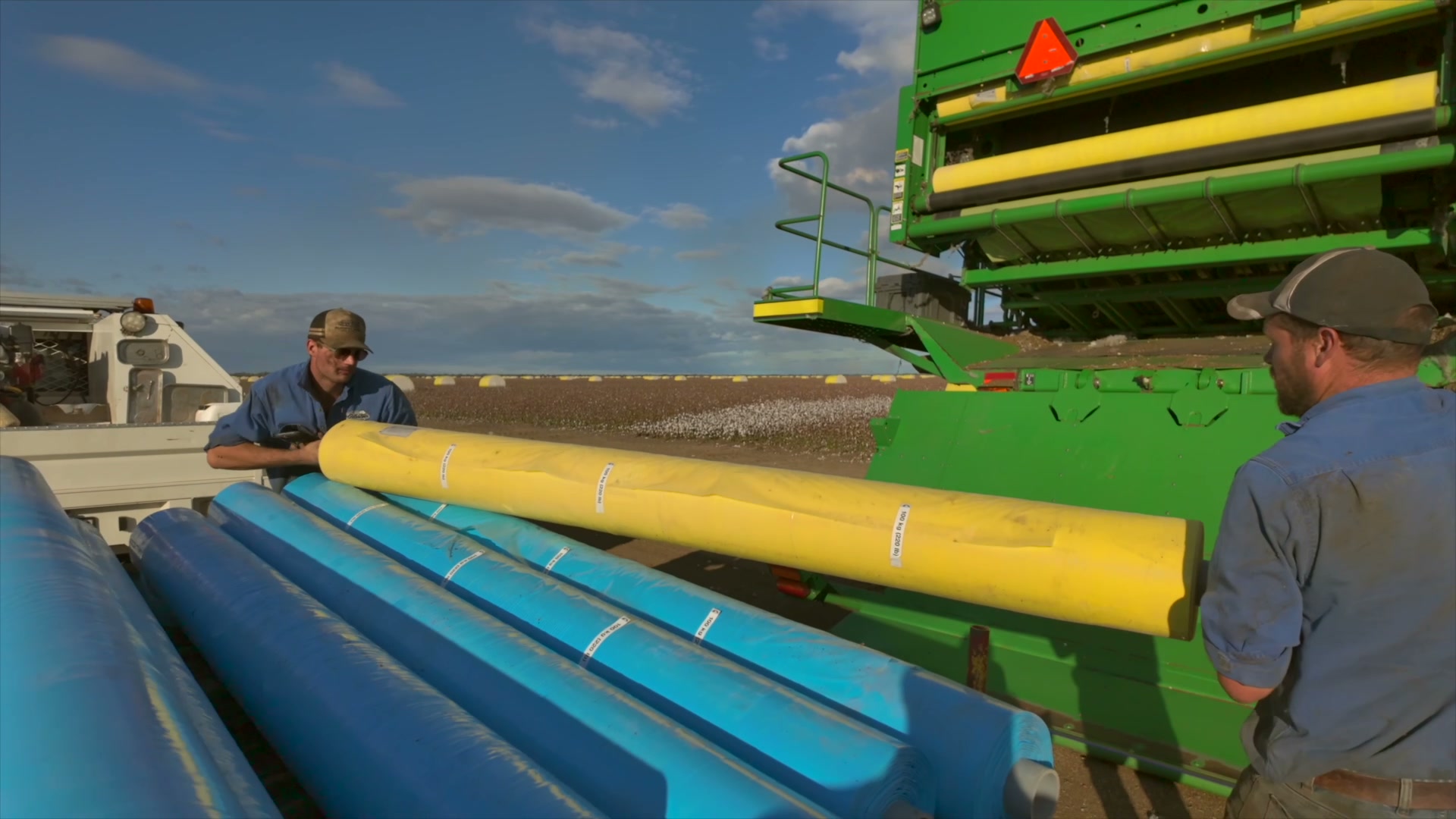 Operators servicing a cotton picker in the field